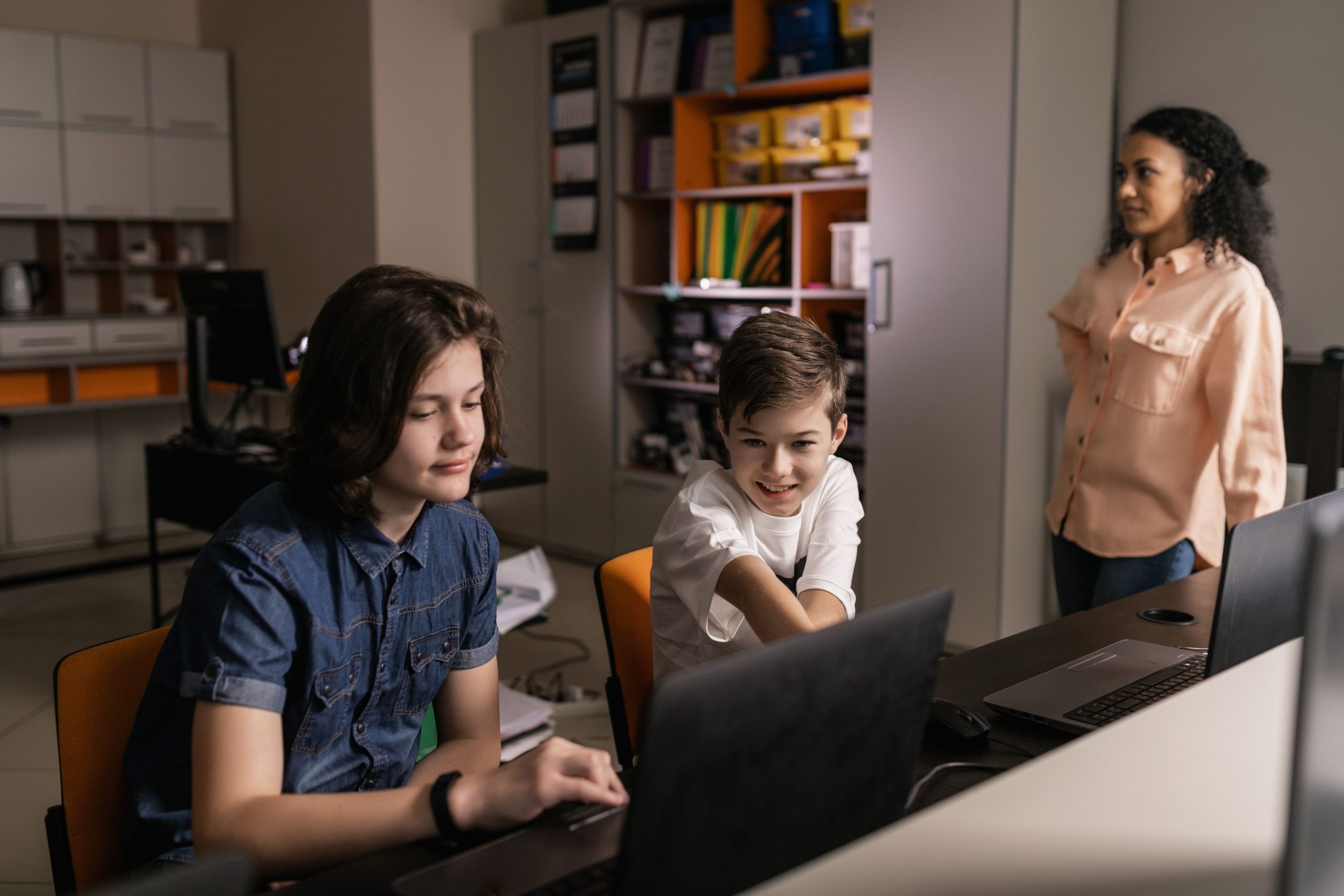 Students using laptops in a classroom with a teacher supervising, illustrating AI detection tools in education