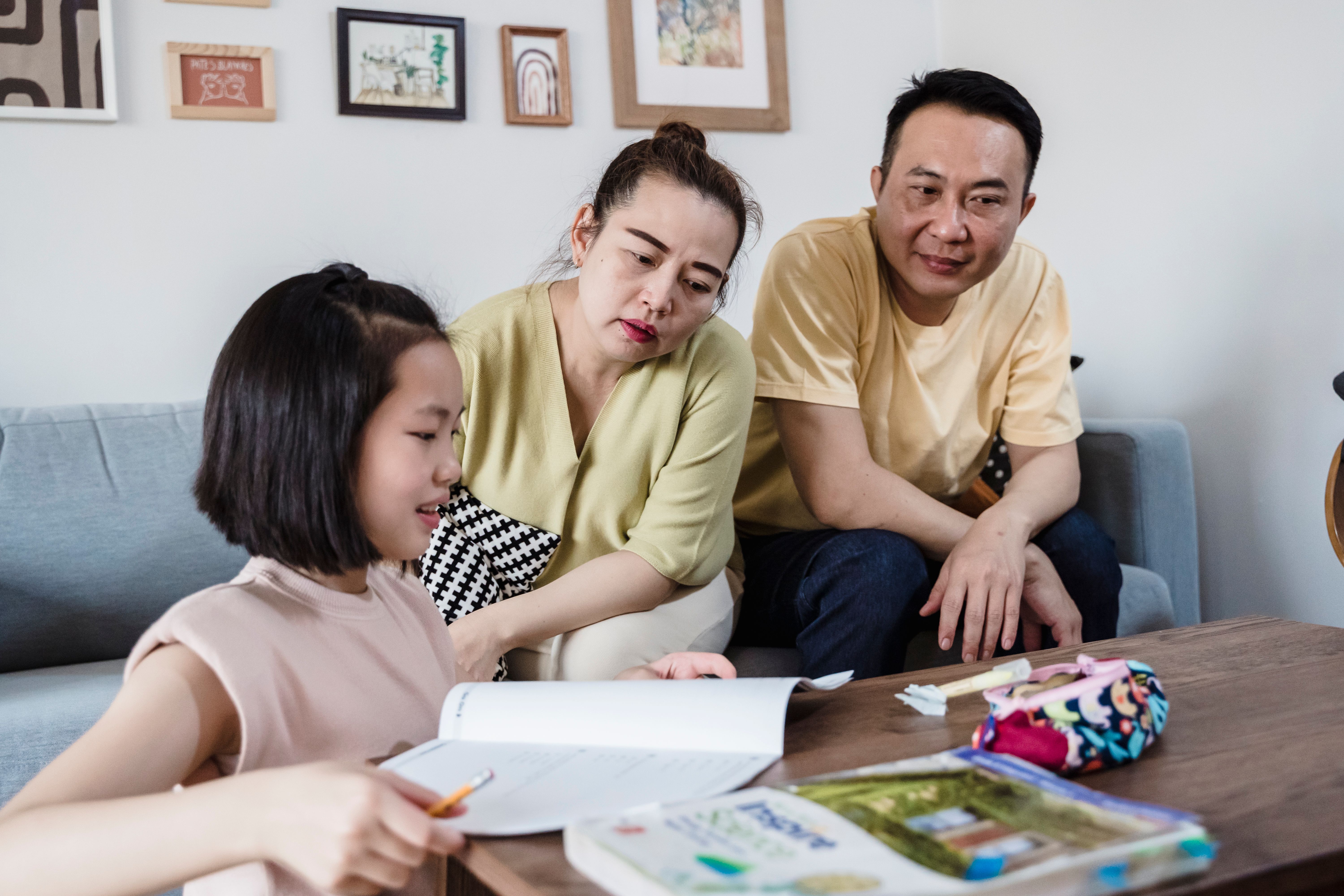 Parents helping their daughter with homework at home, showing family involvement in AI education
